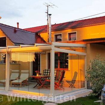Kaltwintergarten mit rahmenloser Schiebe-Verglasung aus Glas und Alu im Abendlicht